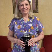 Debra Garreffi, RN at Oakdale Rehabilitation & Skilled Nursing Center in West Boylston, smiling and holding an Oriol Health Care tumbler while wearing purple medical scrubs. Recognized as October 2025 Employee of the Month for her compassionate nursing care.