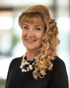 Cynthia Snyder, Director of Nursing, smiling in professional headshot with styled blonde hair and statement necklace